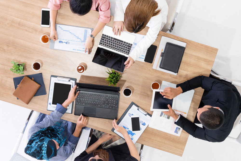 People working on laptops at a table, collaborating and focusing on their tasks.